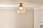 Lampada da soffitto per bagno Nkuku Konnie in ottone con globo in vetro rigato